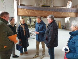 Bauausschuss bei der Arbeit in der Kirche: einige Personen besprechen den Baufortschritt